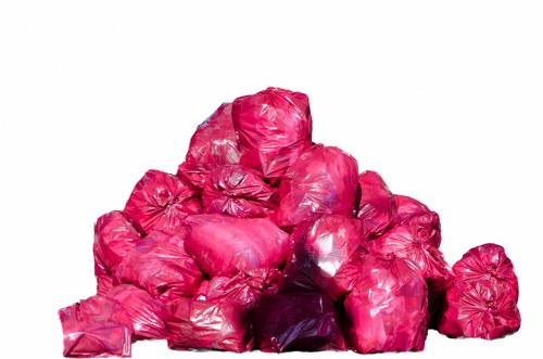 A large pile of tightly packed pink plastic rubbish bags, arranged in a roughly pyramid shape, placed outdoors on a paved surface. The bags appear full and sealed, with some showing slight creasing and reflections on their plastic surface, indicating they are filled with waste materials. The background is plain white, with no other objects or environmental details visible, focusing solely on the collection of rubbish bags. This image illustrates waste that might be handled during rubbish removal services provided by companies like Commercial Waste Great Bookham, situated near the Great Bookham area. The overall scene emphasizes the volume and type of waste typically collected in professional rubbish disposal tasks in the local region, highlighting the importance of proper waste management and clearance efforts.